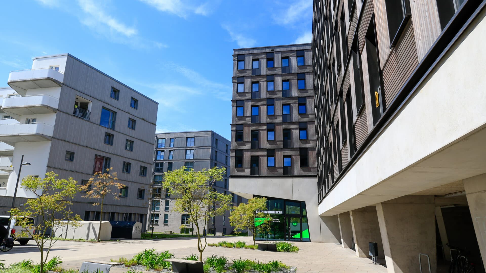 quipped referenz die zimmerei Moderne Wohngebäude mit großen Fenstern und begrüntem Innenhof bei klarem Himmel